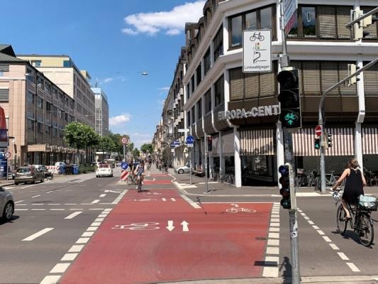 Eine Ampelkreuzung mit indirektem Linksabbiegen für Radfahrende am Adenauerplatz