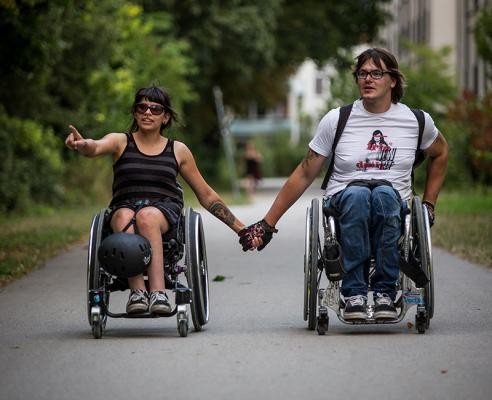 Zwei Rollstuhlfahrer Hand in Hand