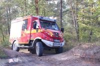 Ein Feuerwehrfahrzeug fährt auf eine Buckelpiste durch den Wald