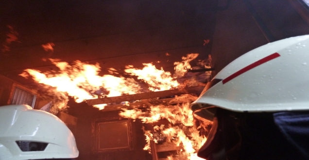 Flammenschein über dem Helm eines Feuerwehrmanns bei einer Übung