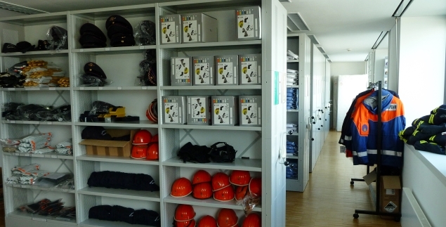Regale der Kleiderkammer die mit Helmen, Handschuhen und weiterer Ausrüstung für Feuerwehrangehörige gefüllt ist.