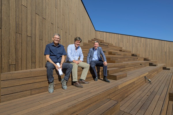 Drei Männer sitzen auf einer holzvertäfelten Treppe auf dem Dach des Congress Centers.