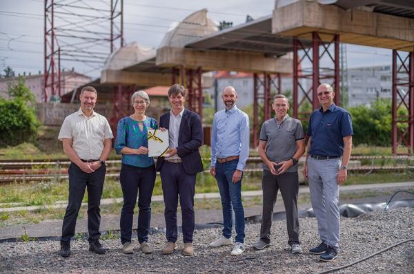 Sechs Menschen stehen vor einer Brückenbaustelle