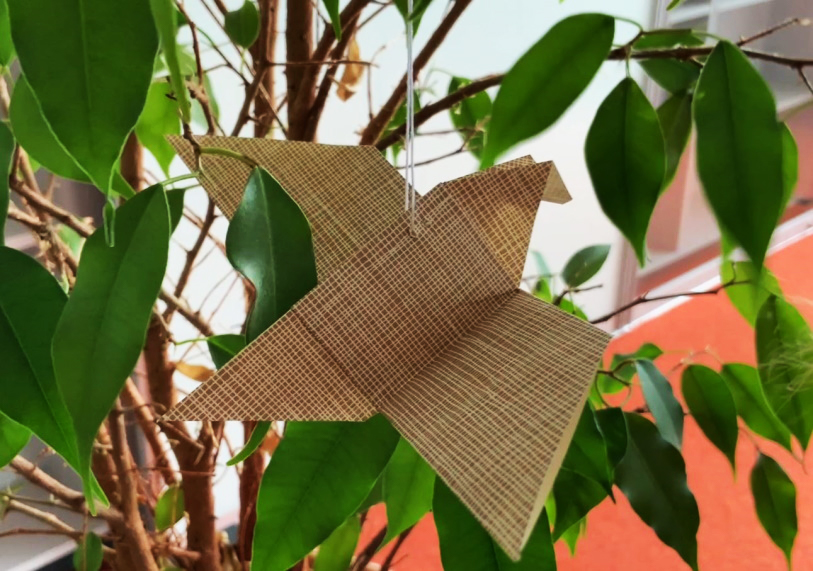 Origamivogel in Grünpflanze hängend