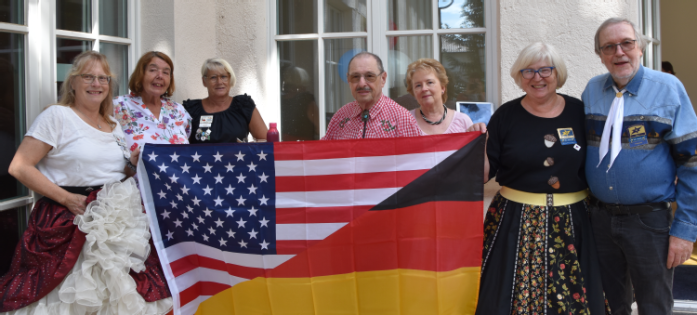 Menschen sitzen auf einer Terrasse und genießen Essen und Trinken.