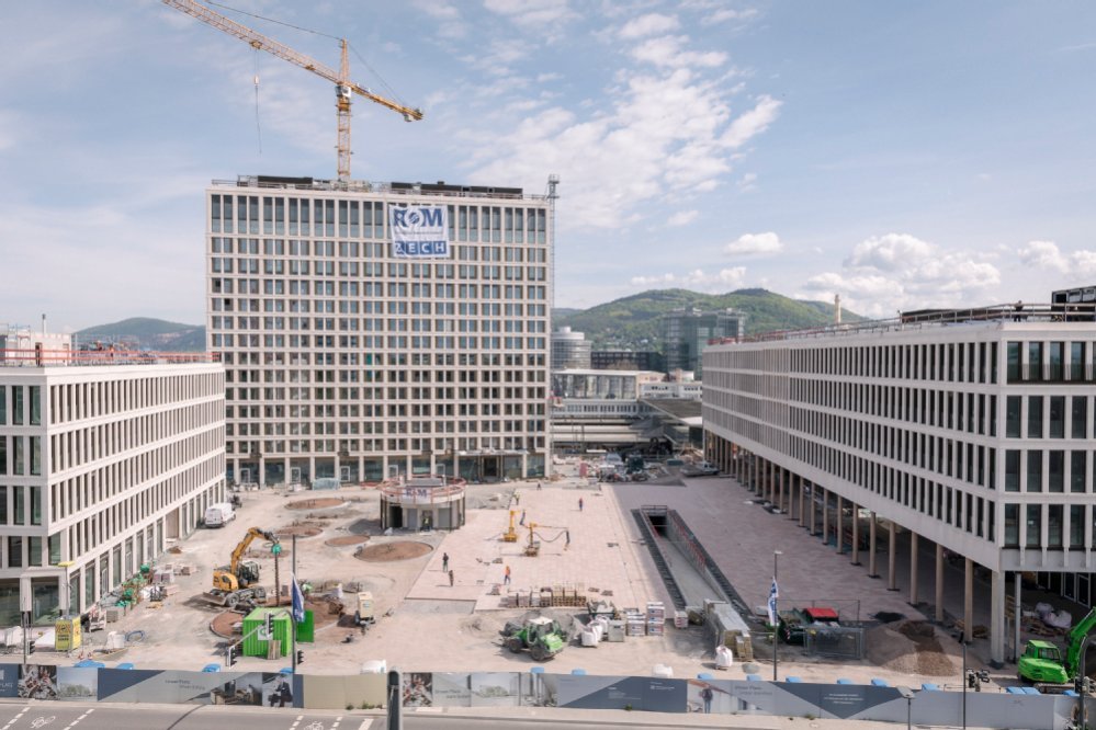 Drei große Gebäude stehen rund um einen großen Platz