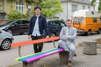 Umweltdezernent Raoul Schmidt-Lamontain und Marius Emmerich von der Koordinationsstelle LSBTIQ+ der Stadt Heidelberg auf einer Regenbogenbank.