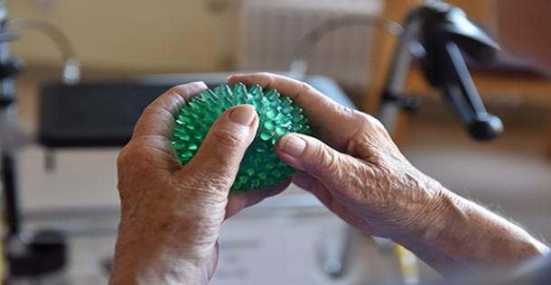 Seniorinnen-Hände mit Igelball und Rollator im Hintergrund