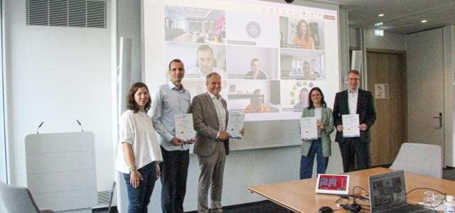 Eine Gruppe steht vor einer Leindwand
