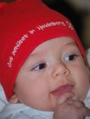 Baby mit Heidelberg-Mützchen (Foto: Kristina Wetzel) Ein Baby trägt eine rote Mütze mit der Aufschrift "Gut behütet in Heidelberg" und lächelt (Foto: Kristina Wetzel)