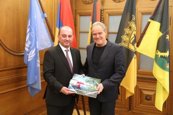 Der Oberbürgermeister und der armenische Bürgermeister im Rathaus mit einem Gastgeschenk.