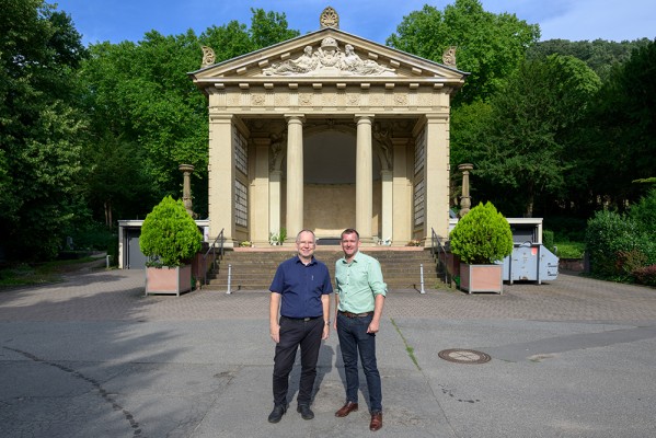 Martin Geißler (links), Leiter des Regiebetriebs Friedhöfe, und Raoul Schmidt-Lamontain, Bürgermeister für Klimaschutz, Umwelt und Mobilität, vor dem Krematorium auf dem Bergfriedhof. (Foto: Rothe) Zwei Herren stehen vor einem kleinen klassizistischen Gebäude.