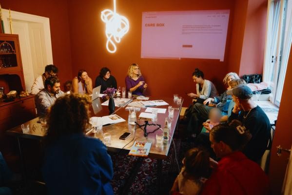 „The Gap Project“ stellt beim IdeenLunch in einem Impulsvortrag ihre neue Plattform „Care Box“ vor. Das Bild wurde beim Launch der „Care Box“ am 1. Oktober aufgenommen. Gruppe von Menschen sitzt an einem Tisch beim IdeenLunch