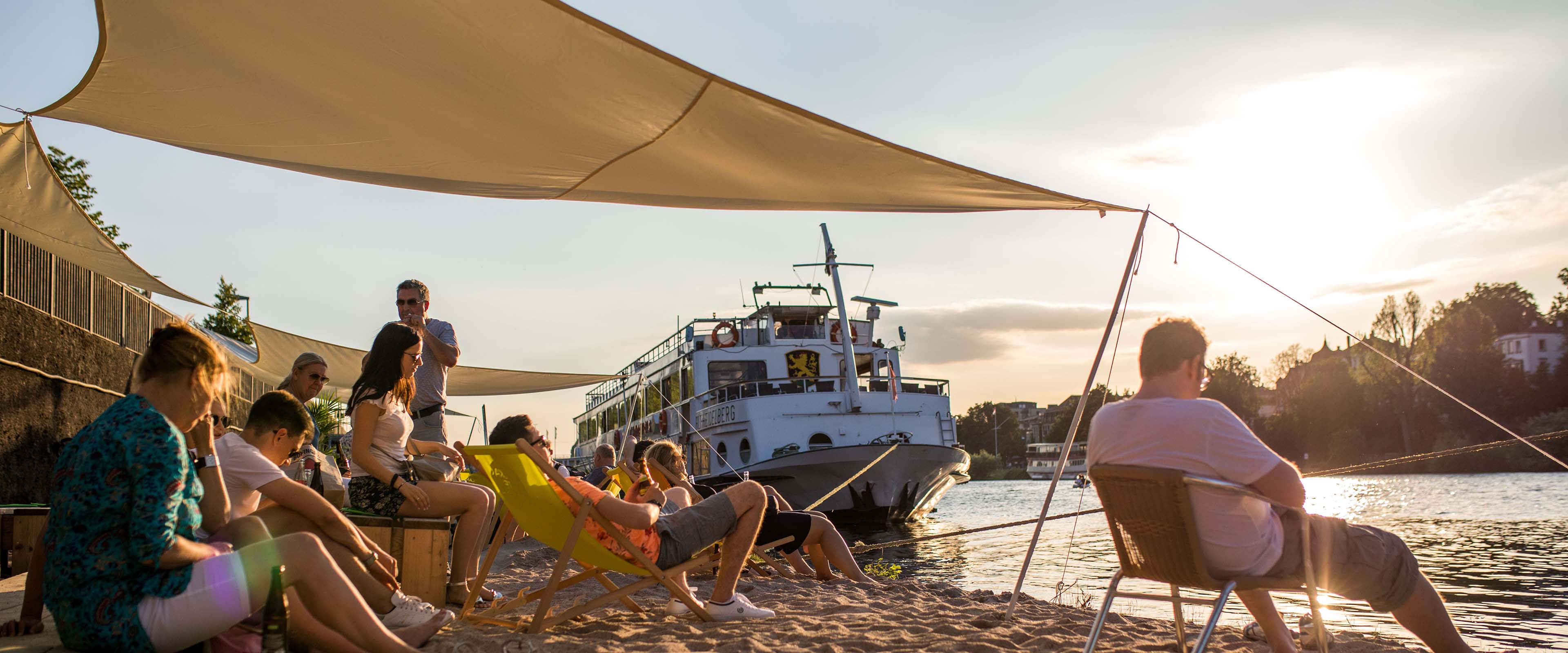 Menschen im Sand am Flussufer bei Sonne