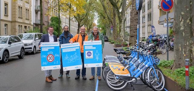 Vier Männer halten Plakate mit Verkehrsregeln. Neben ihnen ist eine Nextbike Statoon