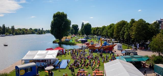 Sicht auf die Neckarwiese. Eine Bühne, Biertischbänke, Pavillons und eine Hüpfburg sind aufgebaut