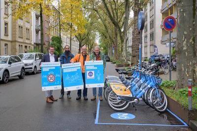 Vier Männer halten Plakate mit Verkehrsregeln. Neben ihnen ist eine Nextbike Statoon