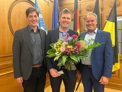 Gruppenfoto. Plöhn hält Blumenstrauß