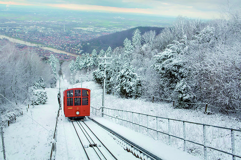 Rote Zahnradbahn fährt in Winterlandschaft den Berg hinauf.