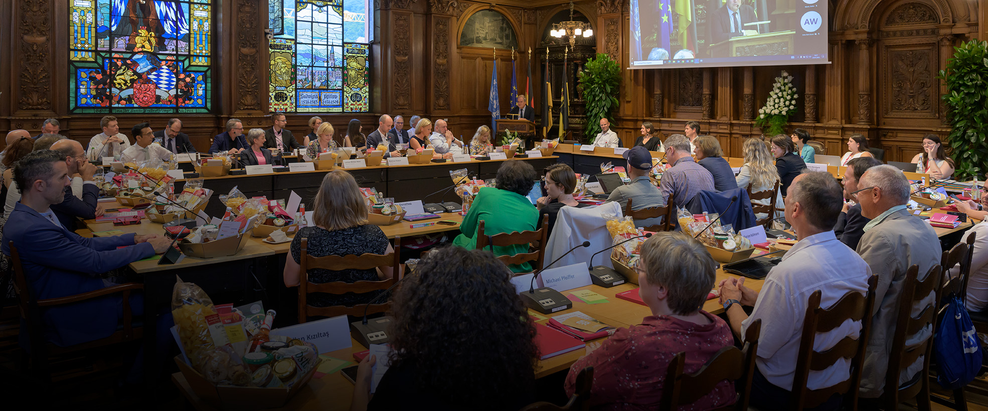 Rätinnen und Räte sitzen an Tischen im Großen Rathaussaal