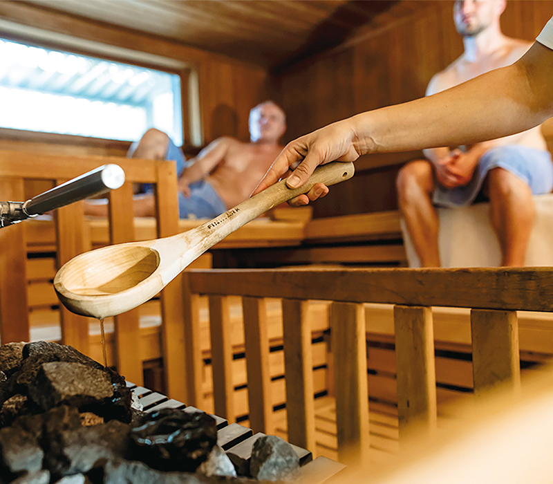 Das Innere einer Holzsauna mit Aufguss und Löffel.